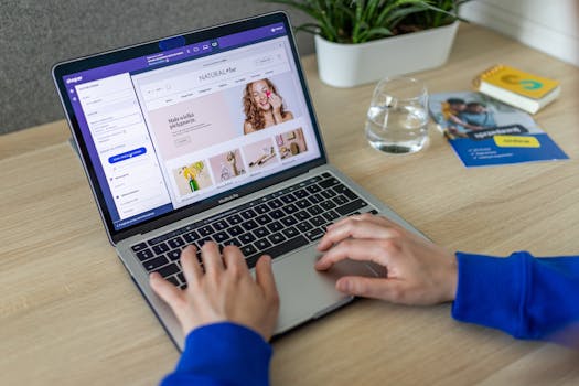 Hands typing on a laptop showing an e-commerce website in a modern office setting.